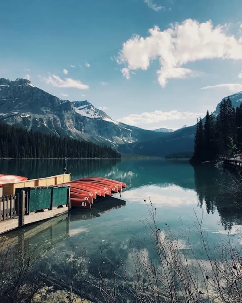 Red canoes at a dock on a calm Canadian mountain lake, cottage country apparel