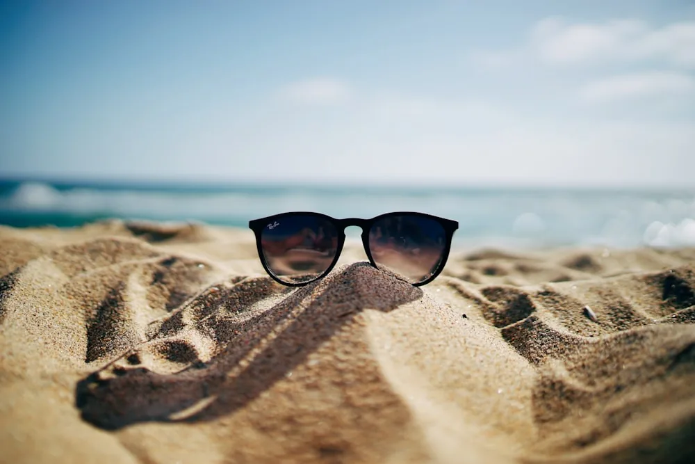 Sunglasses resting on warm beach sand by the sea