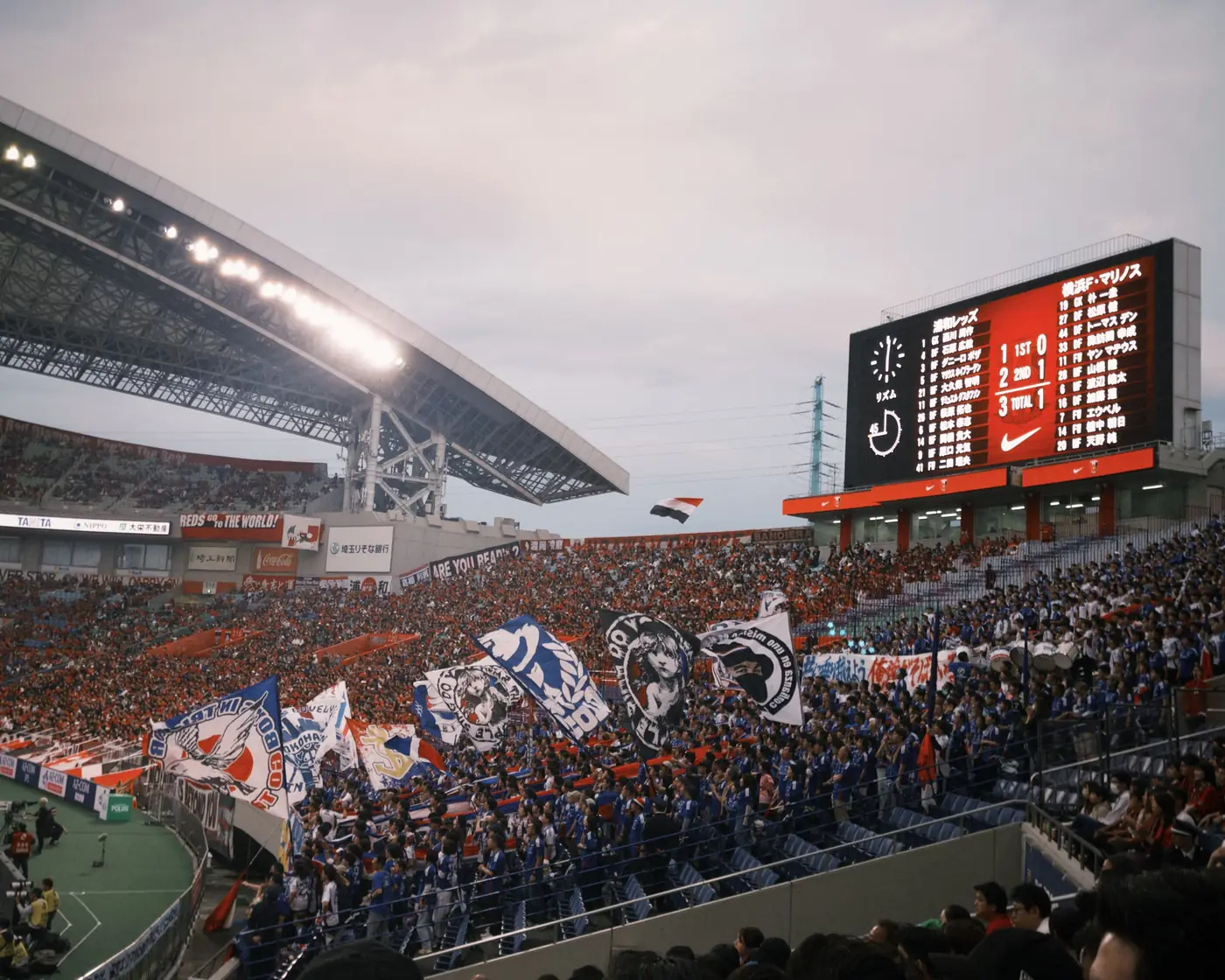 A packed soccer stadium with fans waving flags and banners